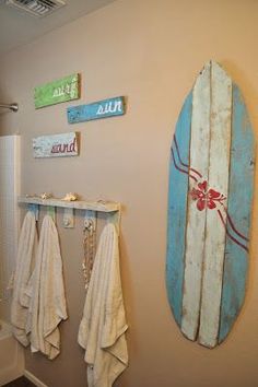 a surfboard is hanging on the wall next to a towel rack in a bathroom