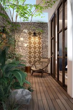 an outdoor room with wooden floors and plants on the outside wall, surrounded by stone walls