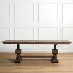 a wooden table sitting on top of a hard wood floor next to a white wall