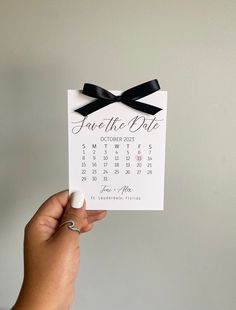 someone holding up a calendar card with a black bow on it