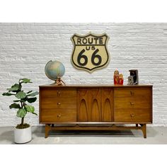 the route 66 sign is on display next to a wooden dresser and potted plant