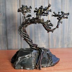 a metal tree sculpture sitting on top of a wooden table