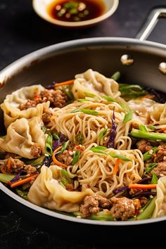 a pan filled with noodles, meat and veggies on top of a table