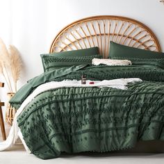 a bed with green comforter and pillows in a room next to a wicker headboard