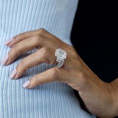 a woman's hand with a ring on top of her finger and a blue shirt