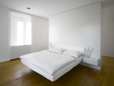 a large white bed sitting on top of a hard wood floor