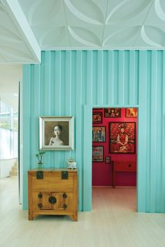 a room with blue walls and wooden furniture in the center, along with pictures on the wall