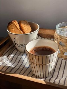 there is a cup of coffee and some cookies on the tray next to each other