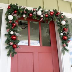 a red front door decorated with christmas decorations