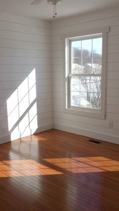 an empty room with wood floors and white walls