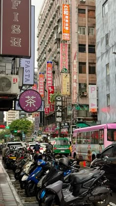 many scooters are parked on the side of the road in front of tall buildings