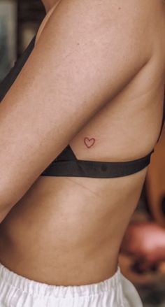 a woman with a small heart tattoo on her chest