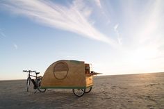 a bike is parked next to a small trailer in the middle of an empty desert