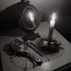 a candle is lit in front of a mirror on a table with utensils