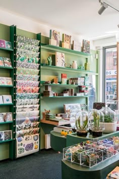 the inside of a jewelry store with green shelves and glass vases filled with flowers