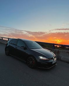 a black car driving down the road at sunset