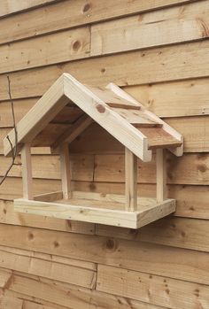 a bird house made out of wood on the side of a wooden building with no roof