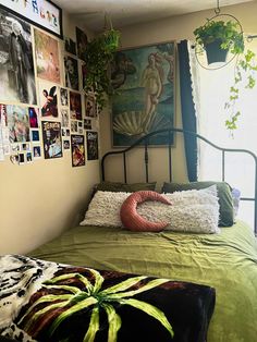 a bed with green sheets and pictures on the wall above it, in front of a window