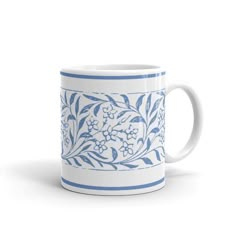 a blue and white coffee mug with floral designs on the outside, in front of a white background