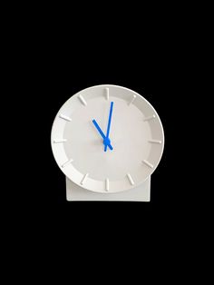 a white clock with blue hands on a black background