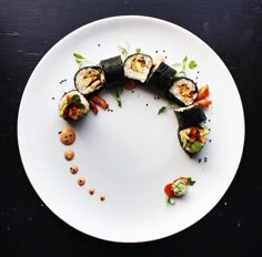 a white plate topped with lots of sushi on top of a black tablecloth