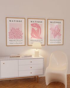 a white chair sitting next to a dresser in a room with posters on the wall