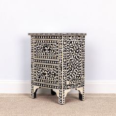 an ornate black and white cabinet against a wall