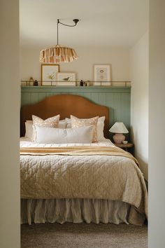 a bed sitting in a bedroom next to a lamp on top of a wooden headboard