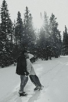 two people are standing in the snow near trees