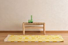 a table with two vases on it next to a yellow and white checkered rug