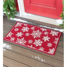 a red door mat with white snowflakes on it in front of a red door