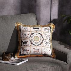 a decorative pillow on a chair with a book and coffee mug in front of it