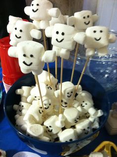 marshmallows with smiley faces are in a bowl on a blue tablecloth