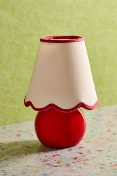 a red vase with a white shade on it