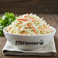 a white bowl filled with coleslaw sitting on top of a table next to a napkin