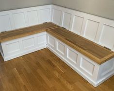 a corner bench with built - in storage underneath it on a hard wood flooring area