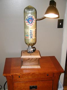 a lamp that is sitting on top of a wooden table next to a drawer with a beer bottle in it