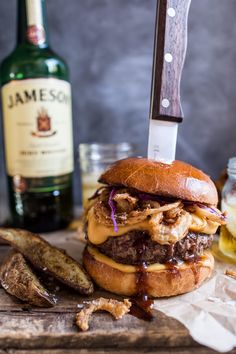 a large hamburger sitting on top of a wooden cutting board with a knife stuck in it