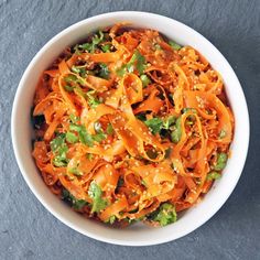 a white bowl filled with carrot salad on top of a table