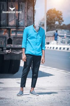 a man standing in front of a truck on the side of the road with his hands in his pockets