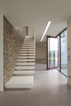 the stairs are made of stone and have white railings on each side, leading to an open area with glass doors