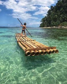 a boy standing on a bamboo raft in the ocean