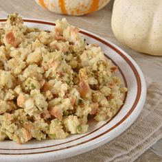 a white plate topped with stuffing on top of a table next to two pumpkins