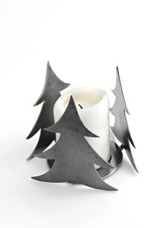 a candle that is sitting in front of a white background with black trees on it