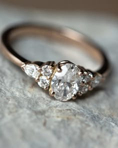 a three stone diamond ring sitting on top of a rock