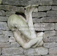 a stone wall that has a statue on it with the words how it feels to know the only way out is through