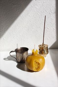 a couple of pieces of fruit sitting on top of a white table next to a cup