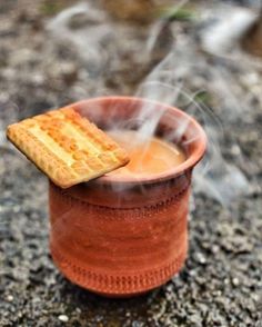 a cup filled with hot liquid and a piece of bread sticking out of the top