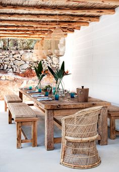 a wooden table sitting under a roof covered in plants