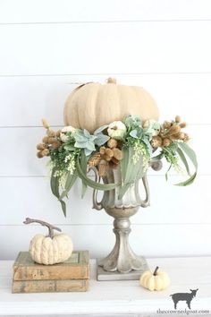 a vase filled with flowers sitting on top of a table next to books and a pumpkin